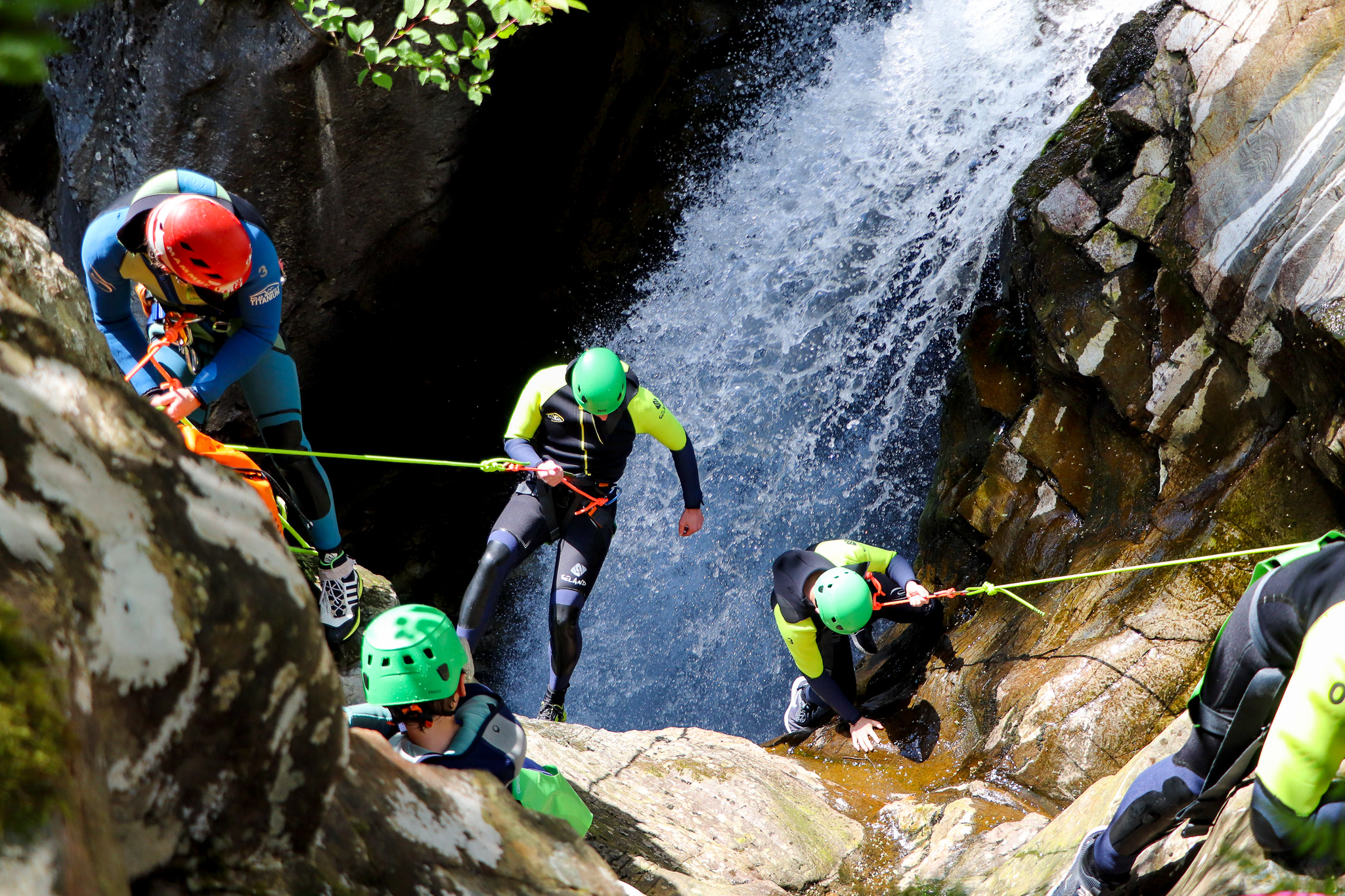 3 Canyoneers abseiling a waterfall under the supervision of their Canyoning guide.